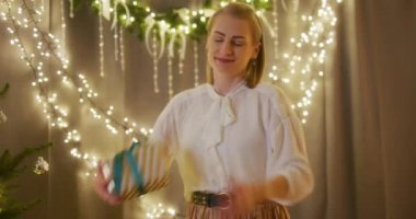 Bir kadın utangaç bir şekilde güzel bir hediye sunar. Sevdikleriyle tatil neşesini paylaşmaya hazırdır..