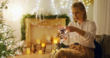 Bir kadın evde Noel süsleri düzenler ve ışıkları çözer. Sıcak bir bayram kutlaması için hazırlanır..