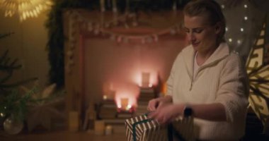 Neşeli bir kadın mutlu bir şekilde Noel hediyelerini hazırlar, yaklaşan tatiller için heyecanlanır..