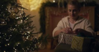 Bir kadın Noel hediyelerini parlak ışıklarla ve arka planda şenlikli bir bokeh ile sarar..