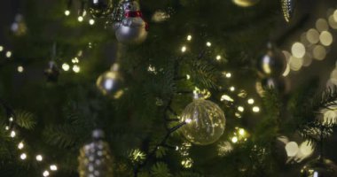 Güzel dekore edilmiş bir Noel ağacına asılı parlak süslemelerin yakın çekim görüntüsü festival ışıklarıyla parlıyor.
