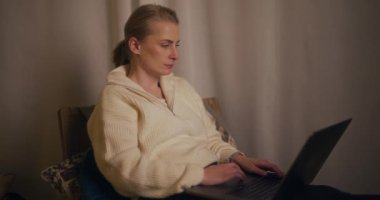 Gece geç saatlere kadar laptopuyla çalışan bir kadın oturma odasında rahatça oturuyor..