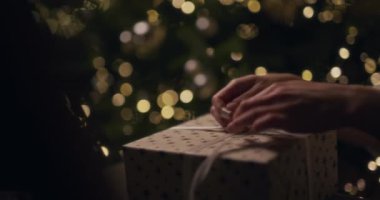 Noel hediyesini dikkatlice paketleyen ve şenlik detaylarına odaklanan bir yakın plan..