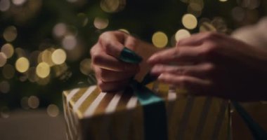 Arkasında parlayan bir ağaç olan bir Noel hediyesini paketlemek, bayram sahnesi yaratmak..