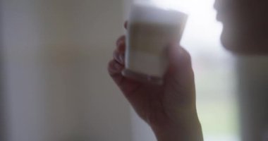 Bir kadın taze demlenmiş latte içer ve mutfağının tadını çıkarır..