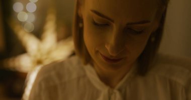 Oturma odasında bir kadın dekorasyon hazırlıyor ve festival sezonu için Noel ışıklarını dikkatlice ayarlıyor..