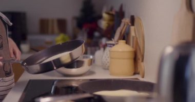 Bir kadın mutfak rutininin bir parçası olarak tavada krep kızartır..