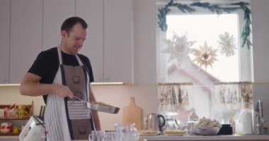 Neşeli bir adam mutfakta yemek pişirirken tavada krep çevirir..