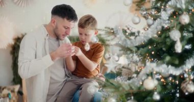 Bir baba ve oğul olarak çekilen aile anı Noel ağacını neşeyle süslüyor.