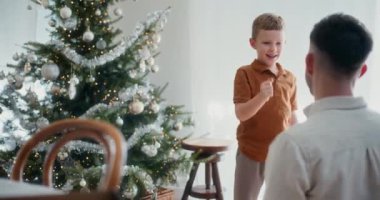 Bir baba ve küçük oğlu neşeli Noel anlarında kağıt-makas-taş oynuyorlar.