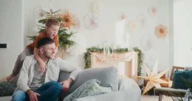 Küçük bir çocuk Noel 'de babalarının sırtına atlayıp kanepede eğlenirken eğlence, kahkaha ve sıcak tatil anlarını paylaşır..