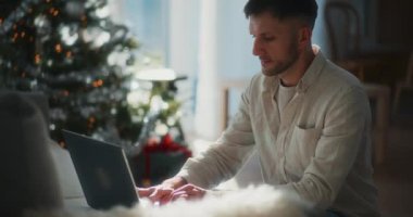 Sıcak bir tatil atmosferiyle çevrili, Noel boyunca bilgisayarında uzaktan çalışan bir adamın silüeti..