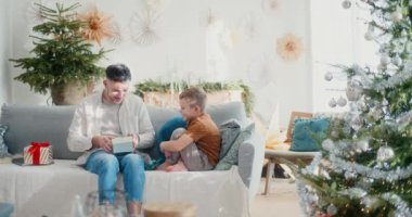 Bir baba, oğlunun verdiği bir Noel hediyesini açar. Noel 'deki özel aile anı için mutlu ve minnettar..