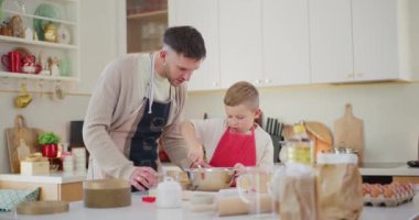 Genç bir çocuk hevesle mutfakta ekmek hamuru karıştırıyor, pişirme becerileri öğreniyor ve babasıyla kaliteli zaman geçiriyor..