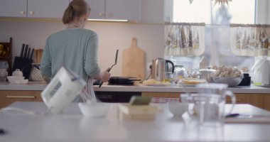 Neşeli bir kadın yemek pişirir, dans eder, mutfakta vakit geçirir..