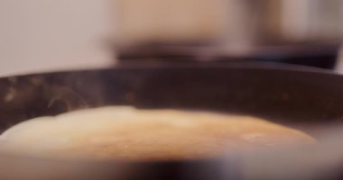 Tavada krep pişirirken iş birliği yapan bir çiftin yakın çekimi..