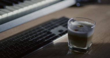 Sıcak bir fincan sıcak latte, rahat bir ortamda masanın üzerine konmuş..