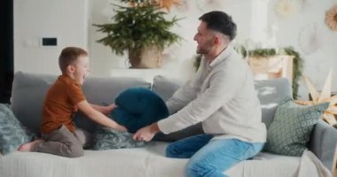 Küçük bir çocuk ve babası Noel 'de koltukta şakacı bir yastık kavgası yapıyorlar, gülüyorlar, eğleniyorlar ve mutlu aile anlarını paylaşıyorlar..