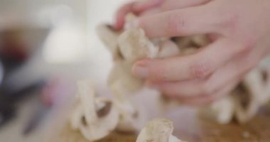 Dilimlenmiş mantarların pişirme hazırlığı için bir kaseye doldurulduğu bir sahne..