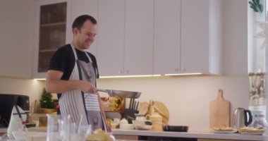 Bir adam ustalıkla mutfakta yemek pişirirken bir krepi havaya fırlatır..