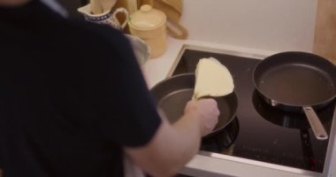 Kızartma tavasında krep çeviren bir adamın yakın plan fotoğrafı..