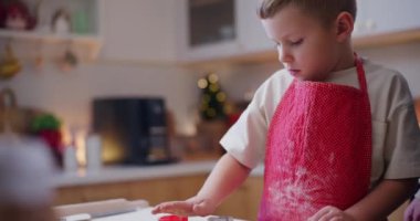 Genç bir çocuk, babasının kurabiyeleri çıkarmasına yardım eder ve onları şenlikli bir aile etkinliği sırasında fırında pişirmeye hazırlar..