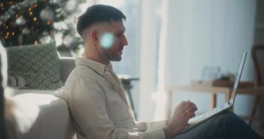 Bir adam bilgisayarını kullanarak internetten alışveriş yapar ve satın almayı kredi kartıyla tamamlar..