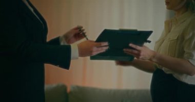 Bir emlakçı, satış anlaşmasını gözden geçirmesi ve imzalaması için bir müşteriye verir..