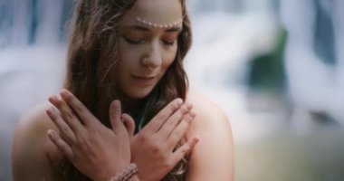 Bir kadın ellerini nazikçe göğsüne koyar meditasyon yaparken, iç benliğiyle derin bir bağ kurar ve huzur bulur..