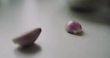 Ahşap mutfak tezgahına yerleştirilmiş iki kabuklu arpacık soğanı, bir tabak için doğranmaya hazır..