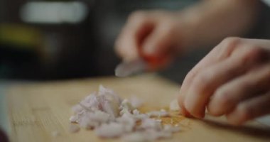 Ahşap bir kesme tahtasının üzerinde, bir tarifte kullanılmaya hazır, ince dilimlenmiş bir soğan..