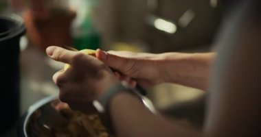 Bir kadın mutfakta patatesleri dikkatlice soyar, ev yapımı akşam yemeği için taze malzemeler hazırlar..