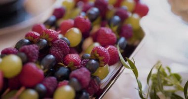 Taze çilek, ahududu ve üzümlerden oluşan renkli bir karışım tepside güzelce dizilmiş..