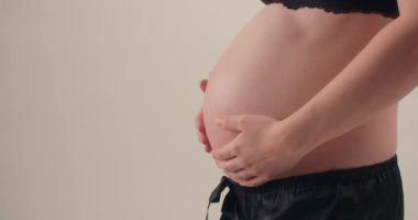 Hamile bir kadın büyüyen karnını şefkatli ve duygusal bir anda okşar..