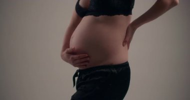 Hamileliğin ileri safhalarında bir kadının karnının detaylı bir yakın çekimi..