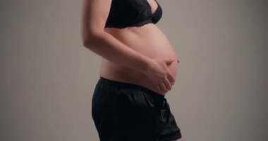 Bir kadın doğmamış çocuğuyla sevgi dolu bir anda karnına hafifçe dokunur..