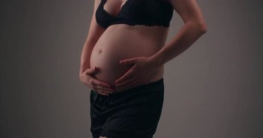 Hamile bir kadının, anneliğin ve yeni hayatın güzelliğini yakaladığı yakın plan bir fotoğraf..