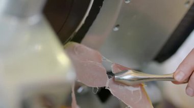 Taze yaşlanmış Parma peyniri et kesme makinesi ile servis ya da pişirme için tam olarak dilimleniyor..