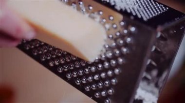 Mutfaktaki metal rendeleyicinin üstünde taze, olgun parmesan rendele..