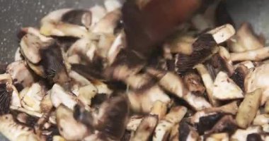 Bir aşçı sıcak tavada taze mantar kızartır lezzetli bir aroma yaratır ve lezzetli bir yemek hazırlar..