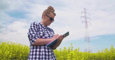 Bir not defterine not alan bir kadın, tarımsal bir tarla tarlasını incelerken. Veri toplama ve ekin sağlığı analizi kavramı.