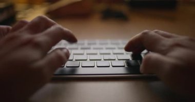Masada çalışan meşgul bir kadın, modern ofis ortamında dizüstü bilgisayara klavye takan elleri kapatıyor..