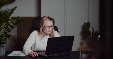 Dizüstü bilgisayarda yazan ve profesyonel bir ofiste projeleri yöneten odaklanmış genç bir kadın..