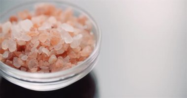 Seramik bir kasede pembe Himalaya tuz kristalleri kırsal bir mutfak yüzeyinde makro bir görüntüde yakalandı..