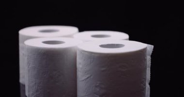 Bir beyaz tuvalet kağıdı karanlık yüzeyde stüdyo ışığında yavaşça dönüyor.