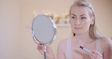 Makyajını bitirdikten sonra aynada yüzünü kontrol eden kadın.