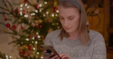 Bir kadın Noel sezonunda akıllı telefon kullanarak internetten alışveriş yapar.