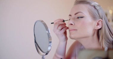 İçerde odaklanmış bir ifadeyle göz kalemi süren bir kadın.