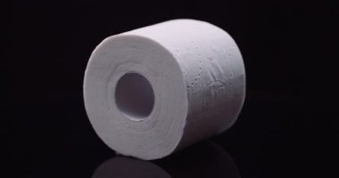 Yumuşak beyaz tuvalet kağıdı yakın çekim makro görünümlü karanlık stüdyo arka planında dönüyor.