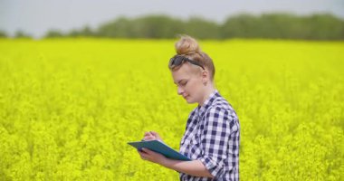 Tarım alanında çalışan bir kadın çiftçi, bir deftere gözlemler ve veriler yazıyor. Alan izleme, veri toplama ve ürün analizi kavramı.